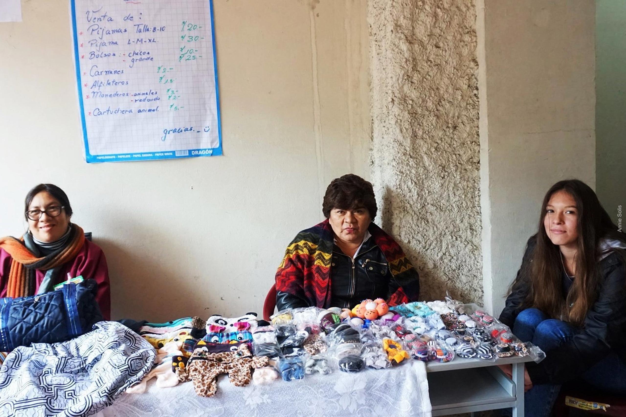3 women displaying their items on a table