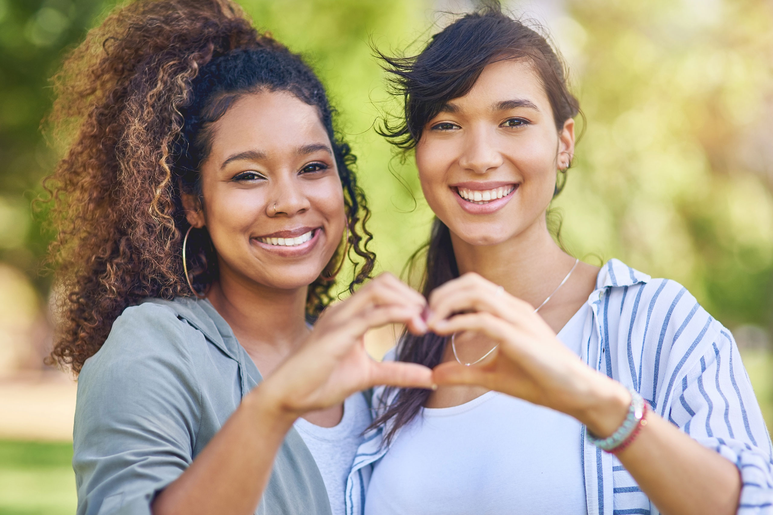 two women making a heart with their hands