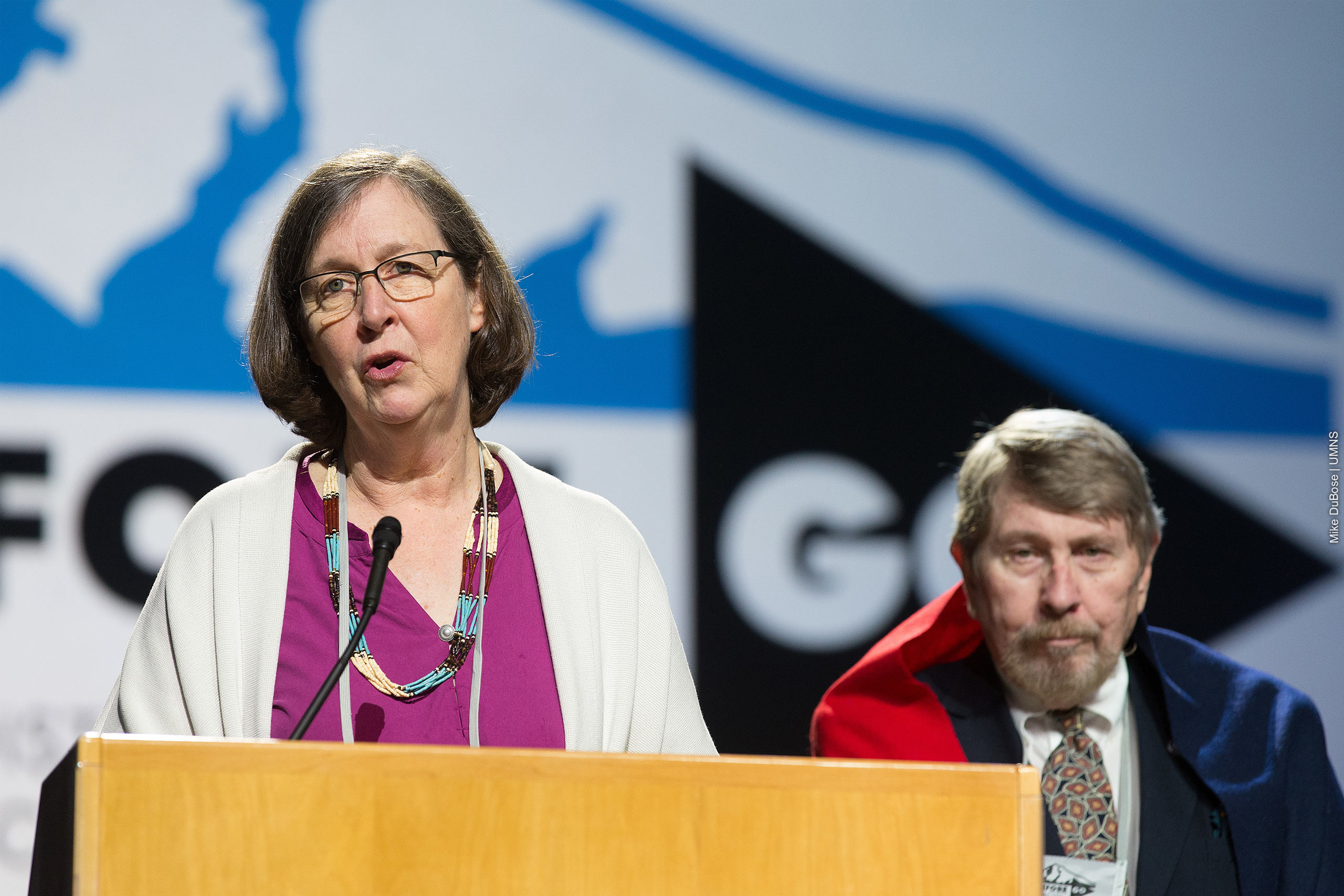 Bishop Elaine Stanovsky introduces Gary L. Roberts at speaker podium.