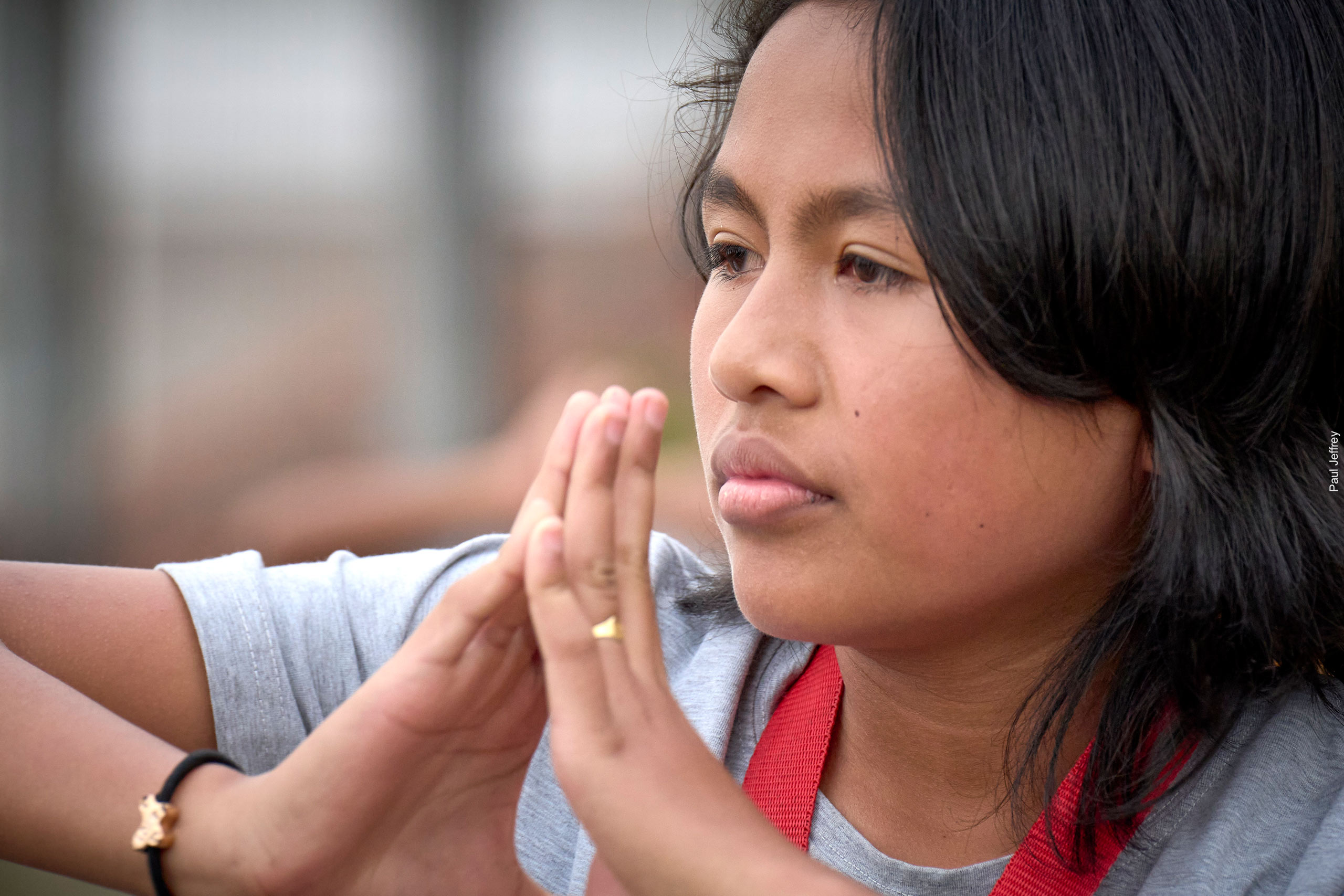 Young woman from Java with hands folded in front of her face.